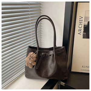 Detail of coffee tote bag with decorative leather strap, buckle and plush bear charm