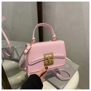 Macro detail of pink crossbody bag with geometric metal lock and smooth leather texture