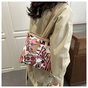 On-body shot of large beige tote bag with vibrant retro graffiti and slender straps