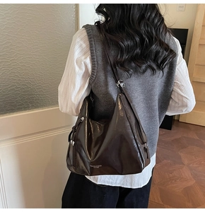 Detailed view of the dark brown leather tote bag showing high-gloss texture and strap