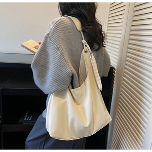 Detail of cream large tote bag with matching pouch and wide strap on model shoulder