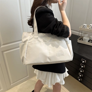 Grande borsa tote minimalista bianco crema con tasca frontale ed etichetta moda donna