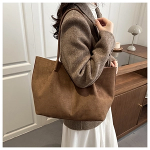 Close-up of a large brown suede tote bag worn on shoulder for autumn fashion style