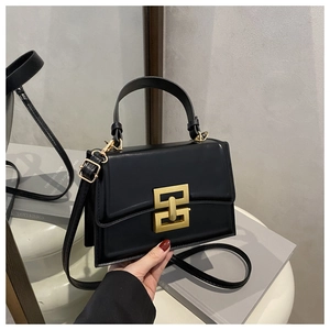 Close-up of black matte leather crossbody bag featuring gold-finished interlocking buckle