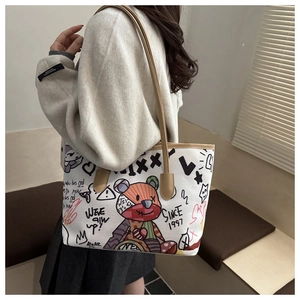 Detail of the doodle tote bag with a colorful bear print and brown shoulder strap