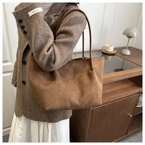 Brown suede tote bag detail showing the soft texture and large capacity on a model