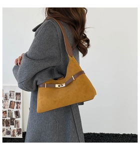 Close-up of mustard yellow suede tote bag with brown leather strap and metal buckle