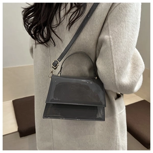 Detail of a shiny dark grey crossbody bag with gold hardware and top handle strap