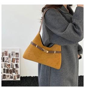 Close-up of mustard yellow suede hobo bag with brown leather strap and gold buckle
