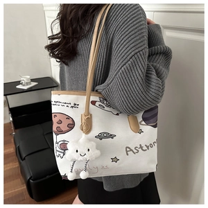 Detail of canvas astronaut tote bag with leather straps and cloud charm accessory