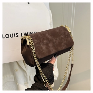 Detail van donkerbruine gewatteerde suède tas met gouden ketting en luxe stiksels