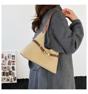 Detail view of a beige suede tote bag with brown leather straps worn over the shoulder