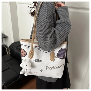 Side view of white canvas tote with space prints and leather straps on model