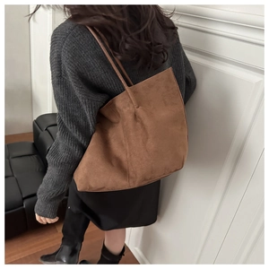 Detailed texture of dark brown suede tote bag carried over a woman's shoulder