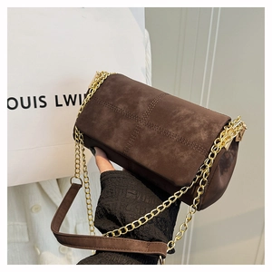 Close-up of brown suede tote bag featuring cross stitching and gold chain strap
