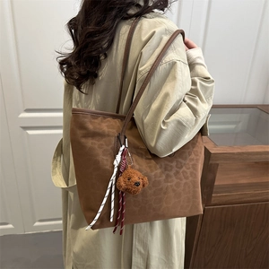 Brown leopard print tote bag with plush dog charm and woven strap details for women