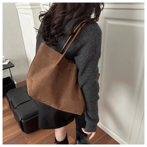 Detail of dark brown suede tote bag showing soft texture and long shoulder strap