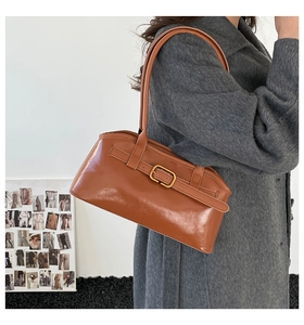 Sac sous le bras rétro en cuir marron avec boucle de ceinture porté par un mannequin