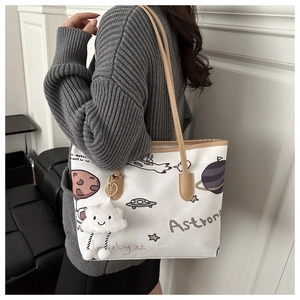 Close-up of white canvas tote bag featuring space astronaut print and cloud charm
