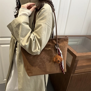 Brown leopard print tote bag with plush charm and scarf, shown as a shoulder bag on a model