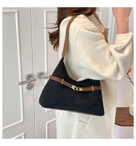 Detail of a vintage black suede tote bag with brown leather strap and gold metal buckle