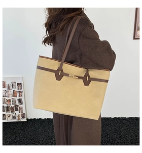Detail view of large faux suede tote bag with golden twist lock and brown trim accents
