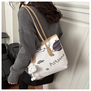 Detailed view of white canvas tote bag with astronaut print and brown leather straps