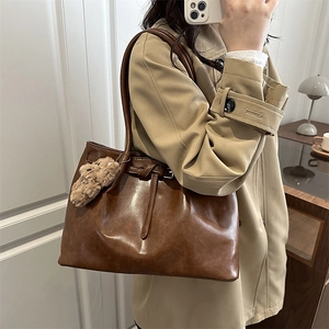 Grand sac cabas marron pour femme avec breloque ours en peluche sur un trench-coat beige