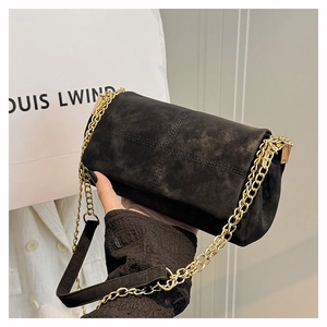 Detail of black crossbody bag featuring matte leather texture and gold chain strap