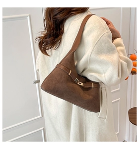 Close-up of a vintage brown suede tote bag featuring a decorative belt and gold buckle