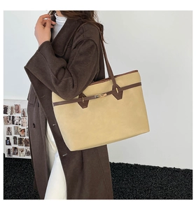 Detail view of large tote bag with metallic lock closure and contrast brown handles