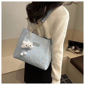 Detail view of light blue tote bag with star texture and plush cloud keychain