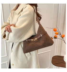 Detail of dark brown suede shoulder bag featuring leather strap and gold metal buckle