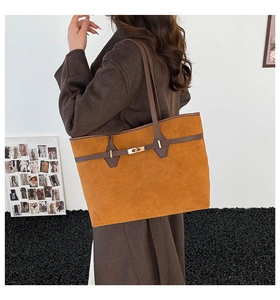 Detail view of large tan suede tote bag with brown straps and golden metal twist lock