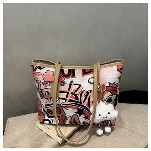Close-up of a graffiti tote bag with abstract red and black print and a plush cloud charm
