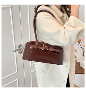 Détail d'un sac d'épaule en cuir verni marron foncé avec boucle dorée et finition brillante