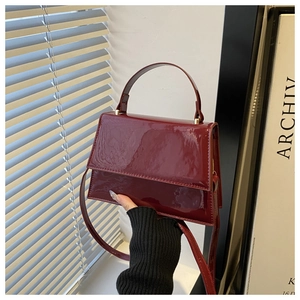 Close-up of deep red glossy patent leather handbag with gold hardware and top handle
