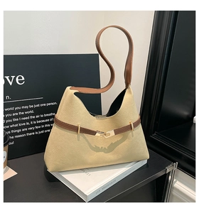 Detailed close-up of beige suede tote bag with brown leather handles and gold metal buckles