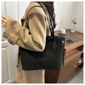 Detail of minimalist black matte tote bag with drawstring on camel coat-wearing model