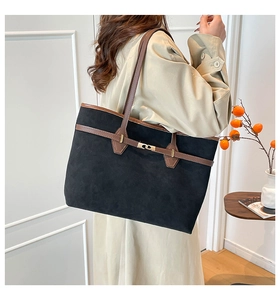 Detail of suede tote bag with brown leather trim and golden buckle on model