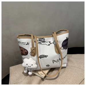 Detail of white canvas tote bag with astronaut print and plush cloud charm accessory