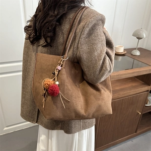 Vintage large brown suede tote bag for women with colorful pompom charm on a casual shoulder strap
