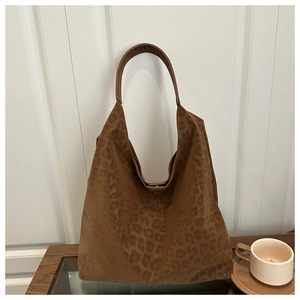 Detail of dark brown leopard print suede hobo bag placed on a wooden table for daily commute