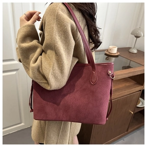 Detailed view of burgundy suede tote bag styled with a classic camel wool coat