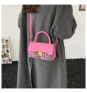 Detail of pink leather handbag with leopard print flap and gold metal clasp on coat