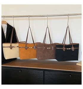 Showroom display of four minimalist suede tote bags in beige, orange, brown, and black colors