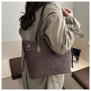 Detail of dark brown suede tote bag featuring drawstring accents and metallic D-rings