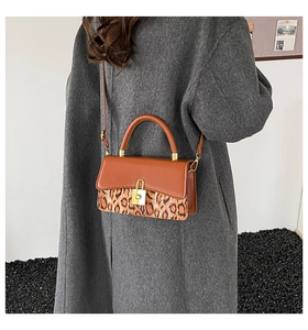 Detail of leopard print handbag with golden clasp styled on a grey autumn coat
