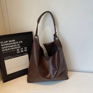 Brown leather hobo tote bag with a wide shoulder strap and modern minimalist design