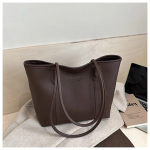 Detail of dark brown tote bag featuring pebbled leather texture and fashion lettering